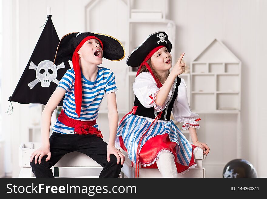 Boy and girl in pirate costumes, playing together On their heads pirate hats with skull and bones.Studio shooting. Boy and girl in pirate costumes, playing together On their heads pirate hats with skull and bones.Studio shooting.