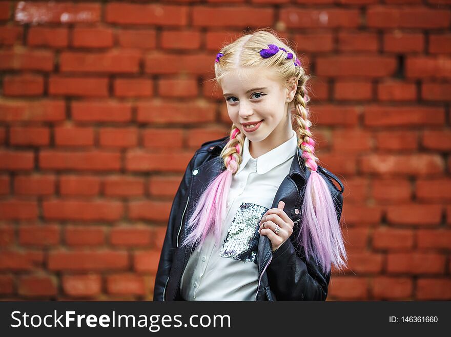 Close up portrait of little beautiful stylish kid girl near red brick wall as background