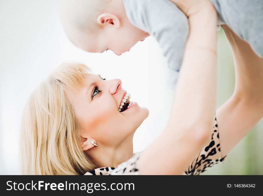 Mother holding her baby up and toching by noses.