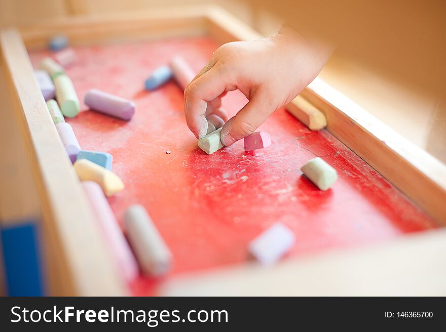 Child`s Hand Holding Chalk Is About To Draw In The Talent Classroom