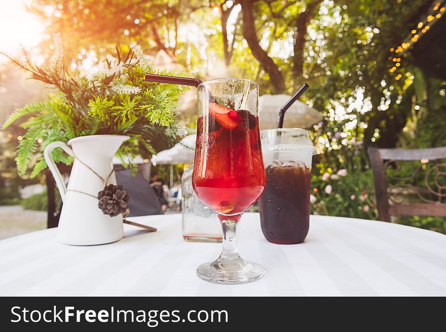 Ice cold berry fruit tea drink and ice coffee with outdoor sunset lighting