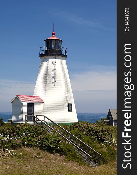 Lighthouse on the hill against a blue sky.