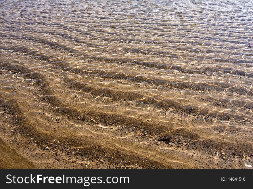 On the beach with ripples on the water surface.