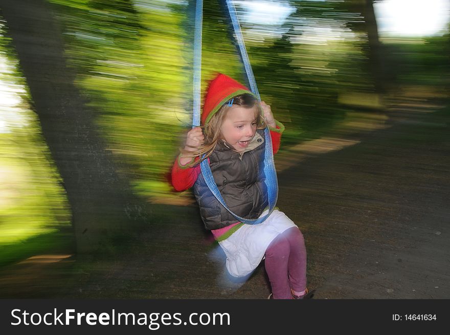 A young girl swinging on a homemade swing in a forest. A young girl swinging on a homemade swing in a forest