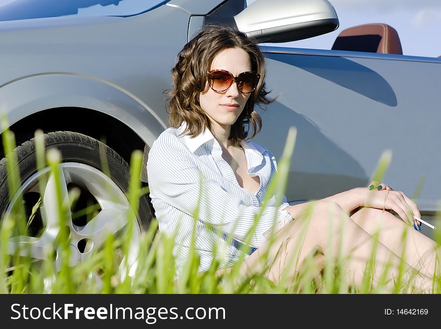 Young woman is sitting near her car and having a rest after a long trip. Young woman is sitting near her car and having a rest after a long trip