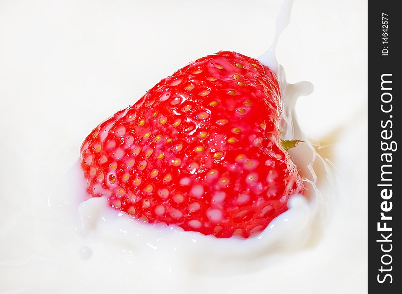 Fresh strawberry splashing into milk or yogurt