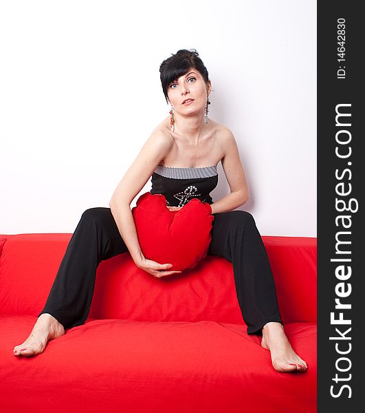 Woman playing with a heart shaped pillow. Woman playing with a heart shaped pillow