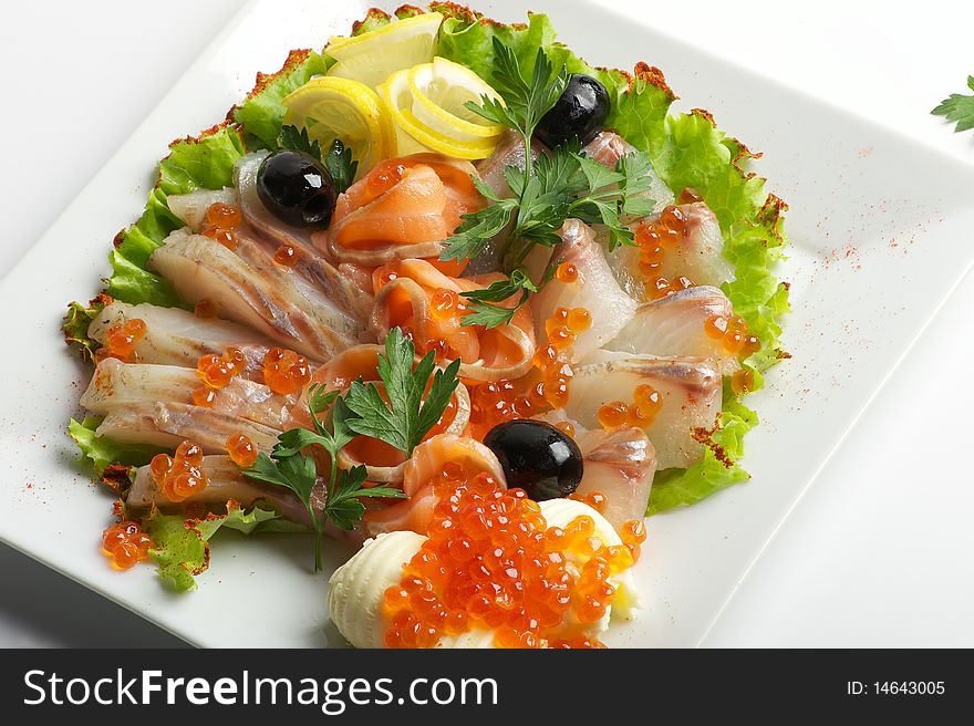 The dish with different kinds of fishes, olives, lemon. The dish with different kinds of fishes, olives, lemon