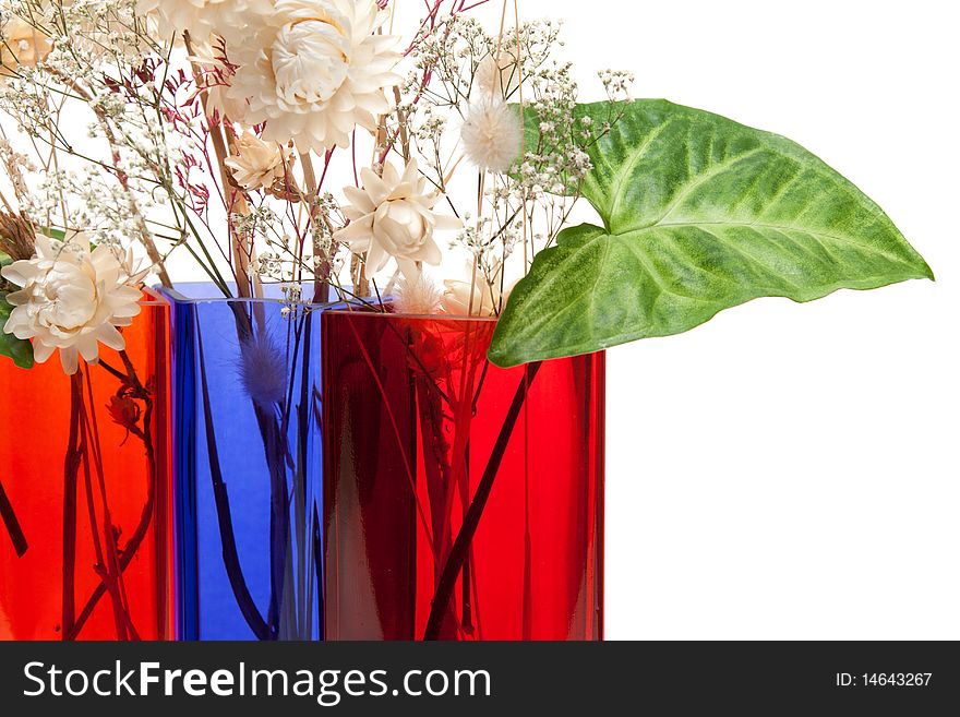 Bouquet from dry herb and green sheet in colour glass vase on white background