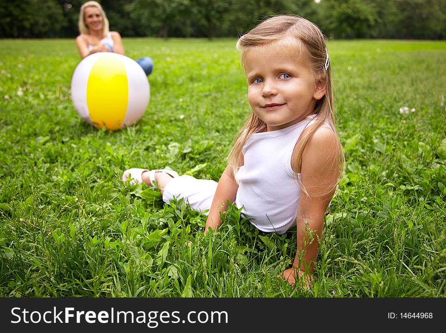 Little girl and her mother are playing with ball; shallow DOF, foces on girl