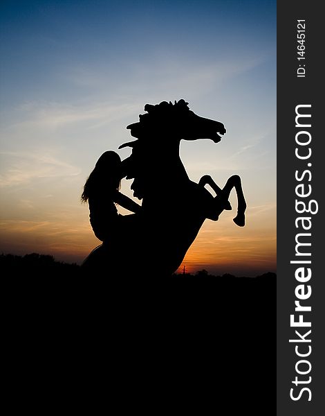 A girl sits on his horse, which reared against the sunset. A girl sits on his horse, which reared against the sunset.