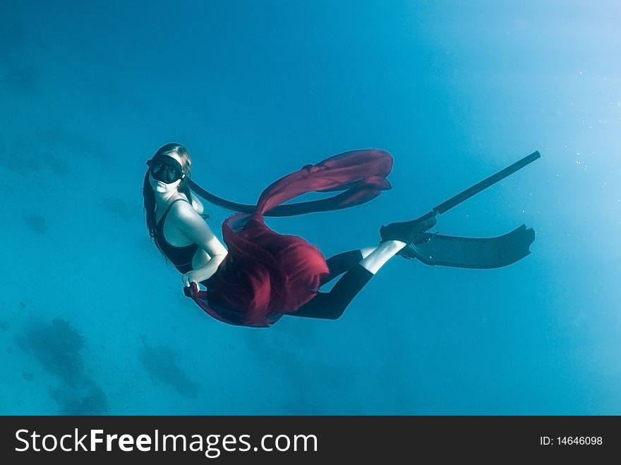 Freediver young girl with a red cloth in the depths of the turquoise sea. Freediver young girl with a red cloth in the depths of the turquoise sea