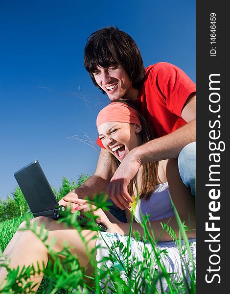 Boy with smile and long-haired girl with notebook on grass. Boy with smile and long-haired girl with notebook on grass