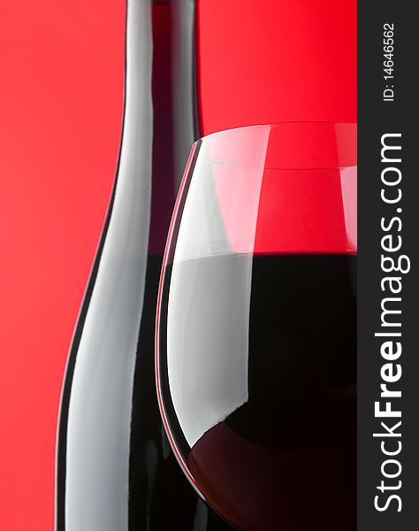 Photo of a wine glass, with a bottle on a red background. Photo of a wine glass, with a bottle on a red background