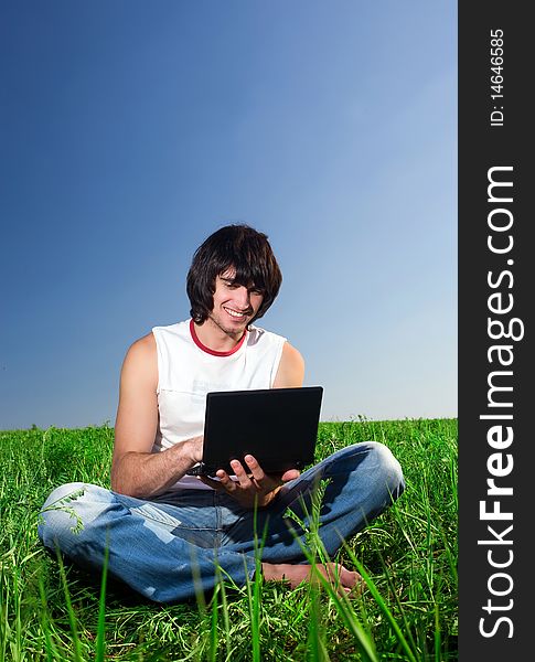 Boy in jeans with notebook on green grass. Boy in jeans with notebook on green grass