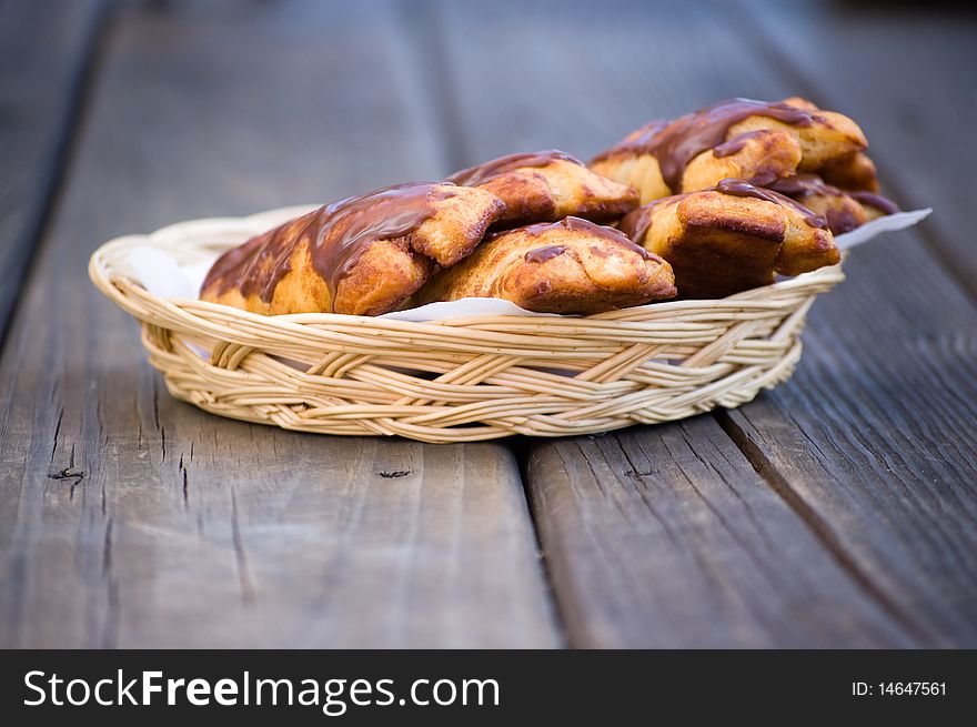 Chocolate buns in a wicker basket on wood boards