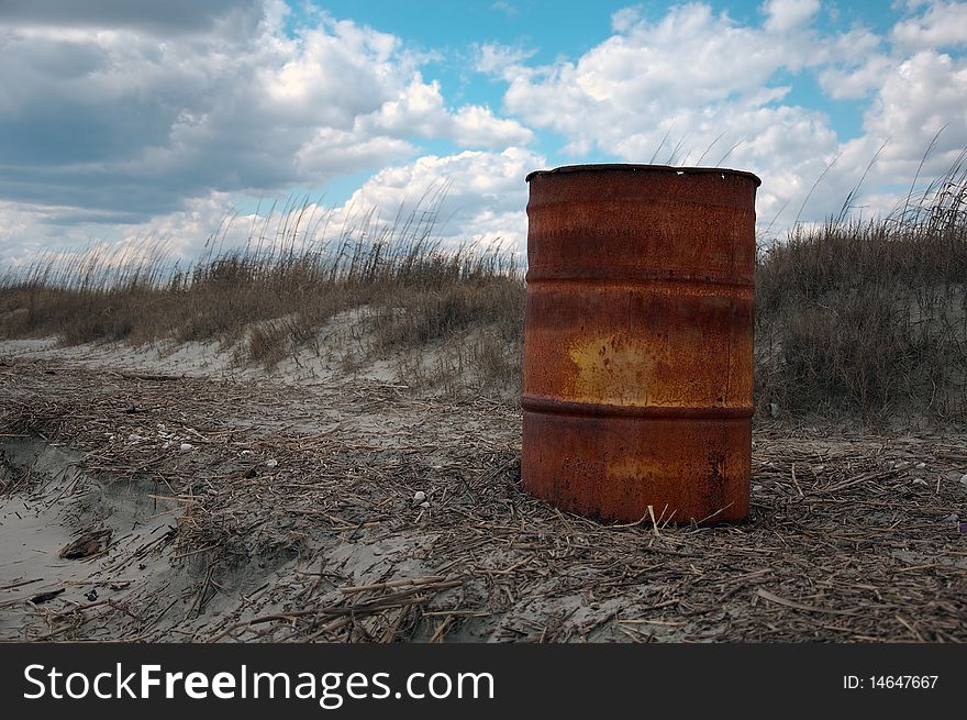 A rusty metal barrel on the beach.