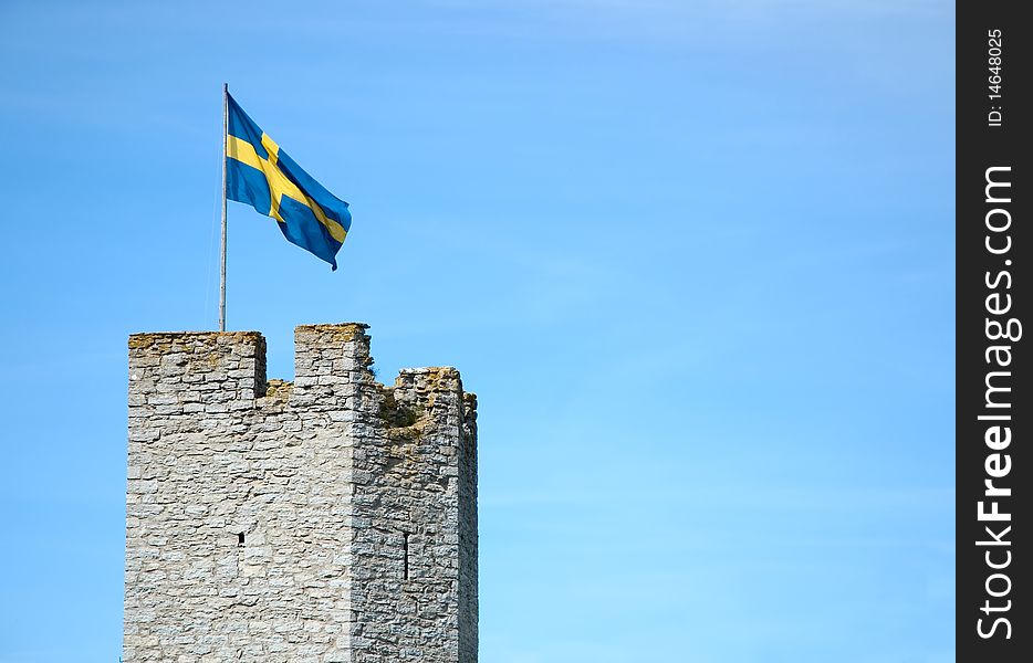 A Swedish flag flying over a medieval wall on Gotland