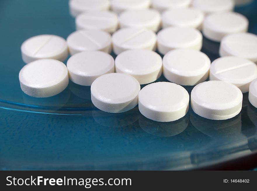 White pressed medicinal pill on blue background. White pressed medicinal pill on blue background