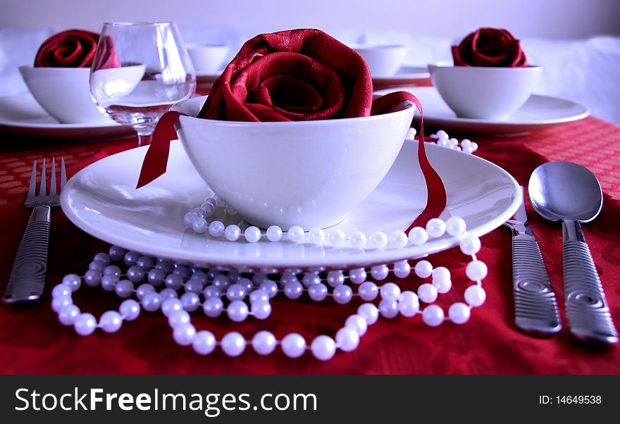 Tea cups with fabric rose and beeds on red tablecloth. Tea cups with fabric rose and beeds on red tablecloth