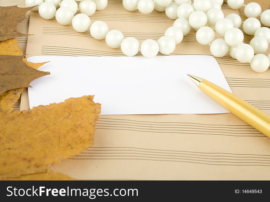 Old sheet music sheet of paper which has a handle, white pearl and maple leaves in autumn. Old sheet music sheet of paper which has a handle, white pearl and maple leaves in autumn