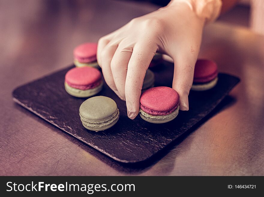 Lets try. Close up of female hand that taking macaron from plate, going to sell it. Lets try. Close up of female hand that taking macaron from plate, going to sell it
