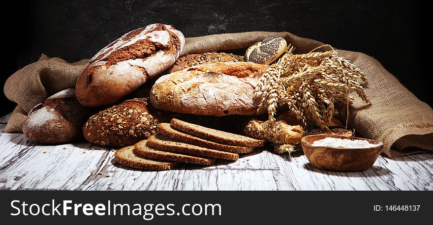 Assortment of baked bread and bread rolls on rustic white bakery table background