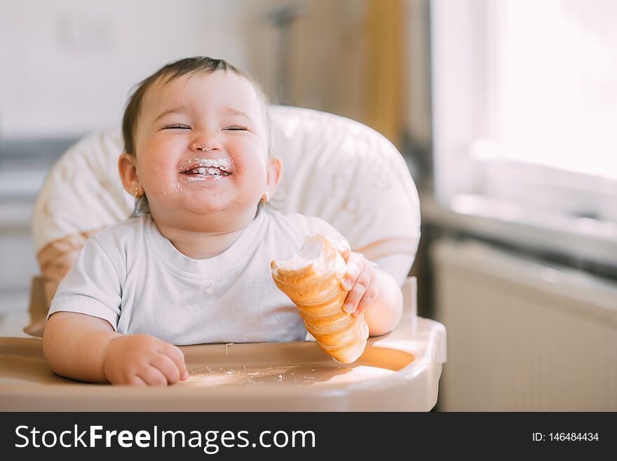 The baby in the kitchen greedily eats delicious creamy tubes filled with vanilla cream