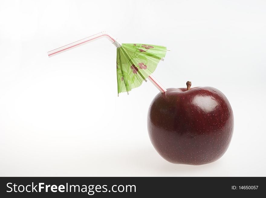 Red apple with straw and umbrella isolated