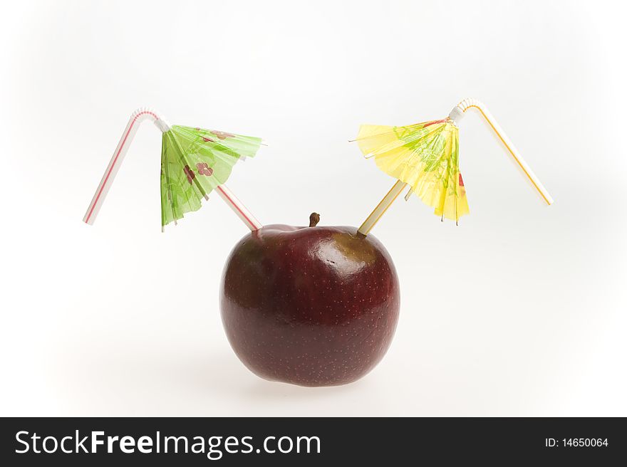 Red apple with two straws and umbrellas isolated