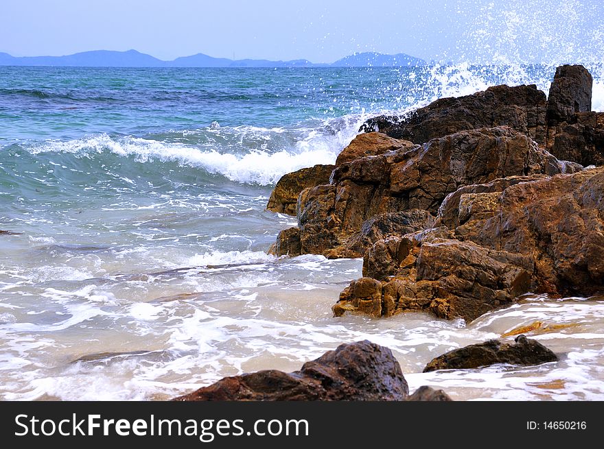 Reef and surge on beach, with white wave and spray.