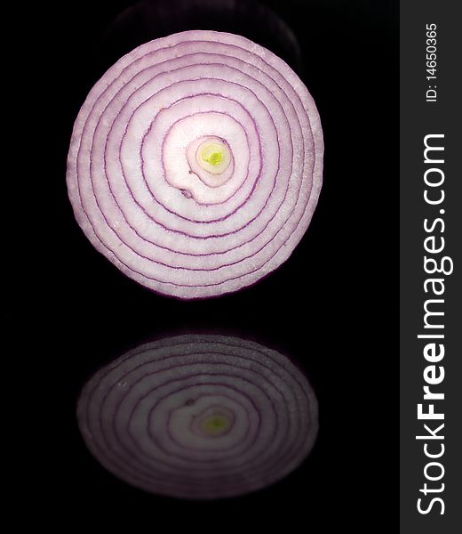 A red onion isolated against a black background