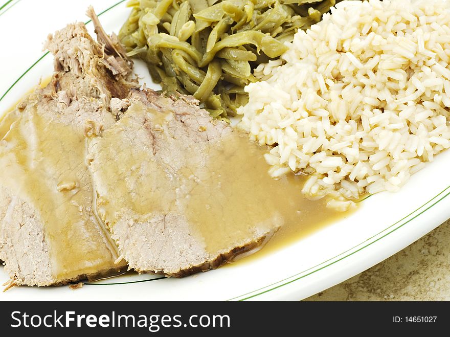 A sliced roast beef dinner with rice and green beans