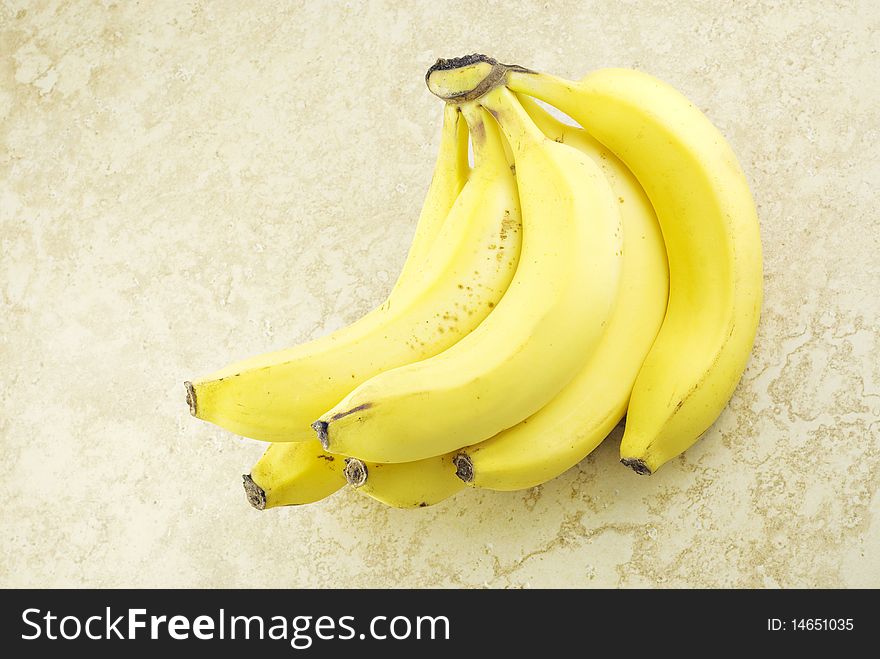 A bunch of ripe bananas on a beige background