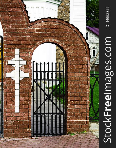 Brick gate with a cross conducting in a building churches. Brick gate with a cross conducting in a building churches