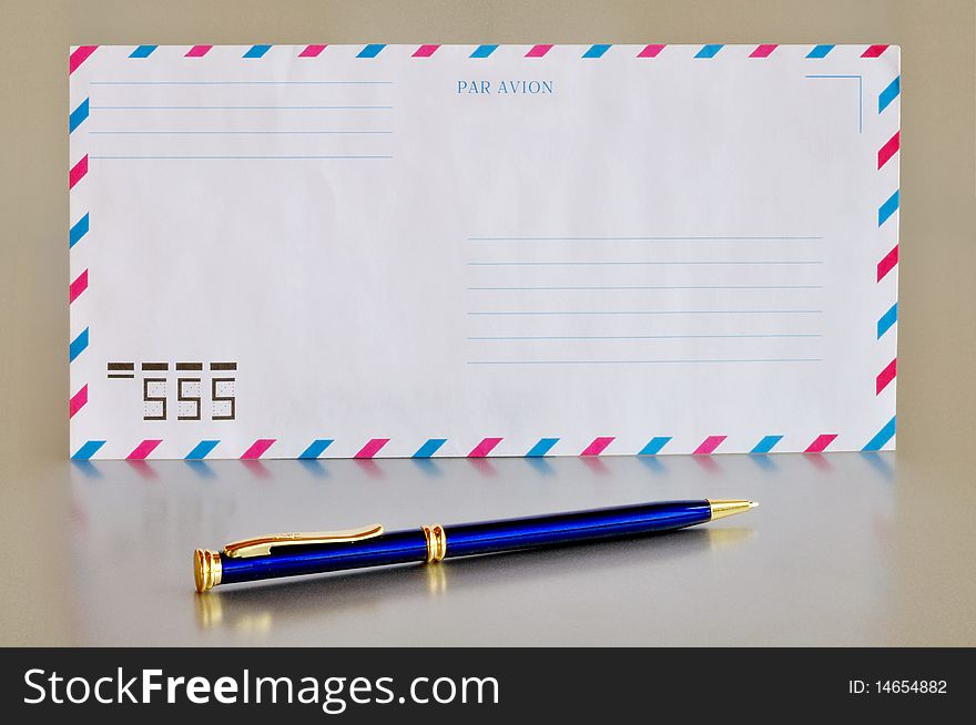 Airmail envelope and blue pen on a homogeneous background