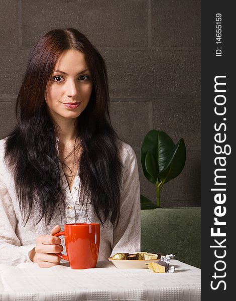 Beautiful lady drinking tea with chocolate candies