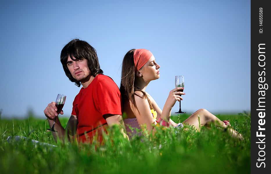 Long-haired girl in kerchief and boy with wineglasses on grass