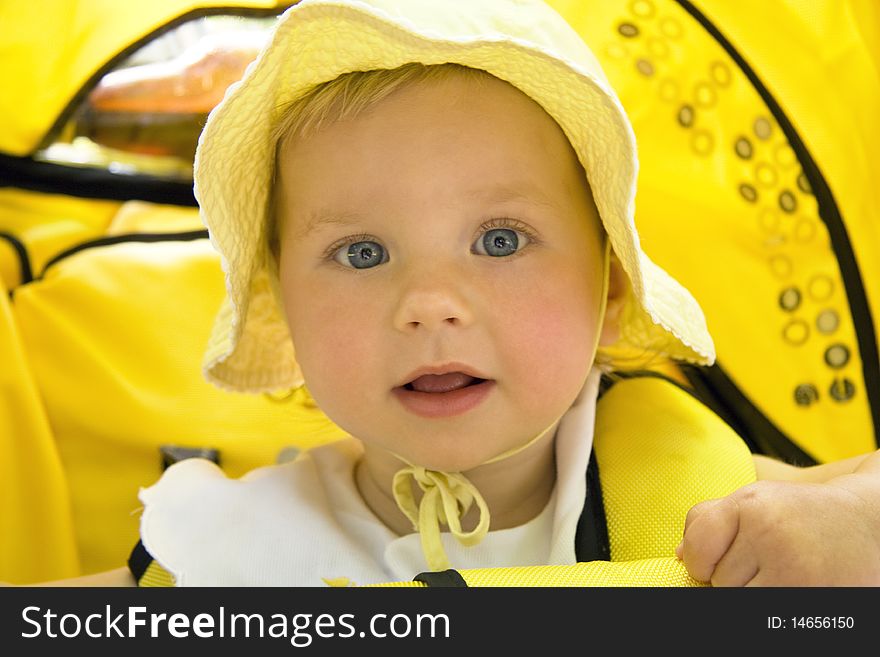 The surprised girl with blue eyes sits in a children's carriage. The surprised girl with blue eyes sits in a children's carriage