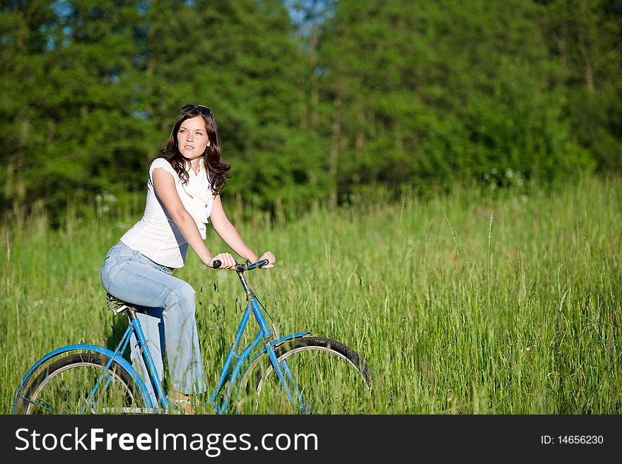 Woman with old-fashioned bike in meadow on sunny day