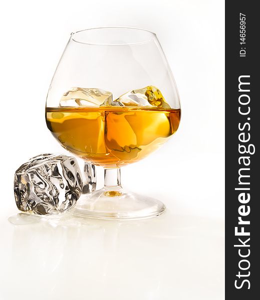 Glass of cognac with ice in a light environment. Glass of cognac with ice in a light environment