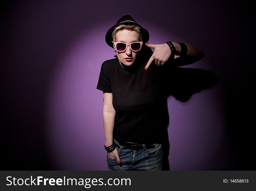 Fashion woman in hat with pink eyeglasses on a lilac background