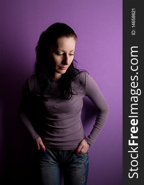 Lonely woman grieves in jeans on purple background. Lonely woman grieves in jeans on purple background