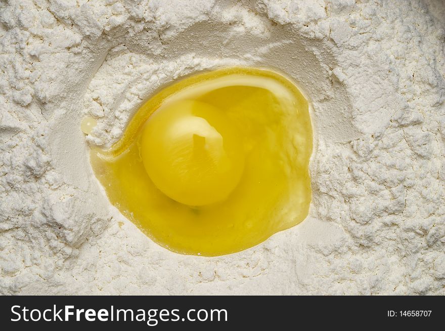 Smashed egg yolk inside the flour macro shot background. Smashed egg yolk inside the flour macro shot background