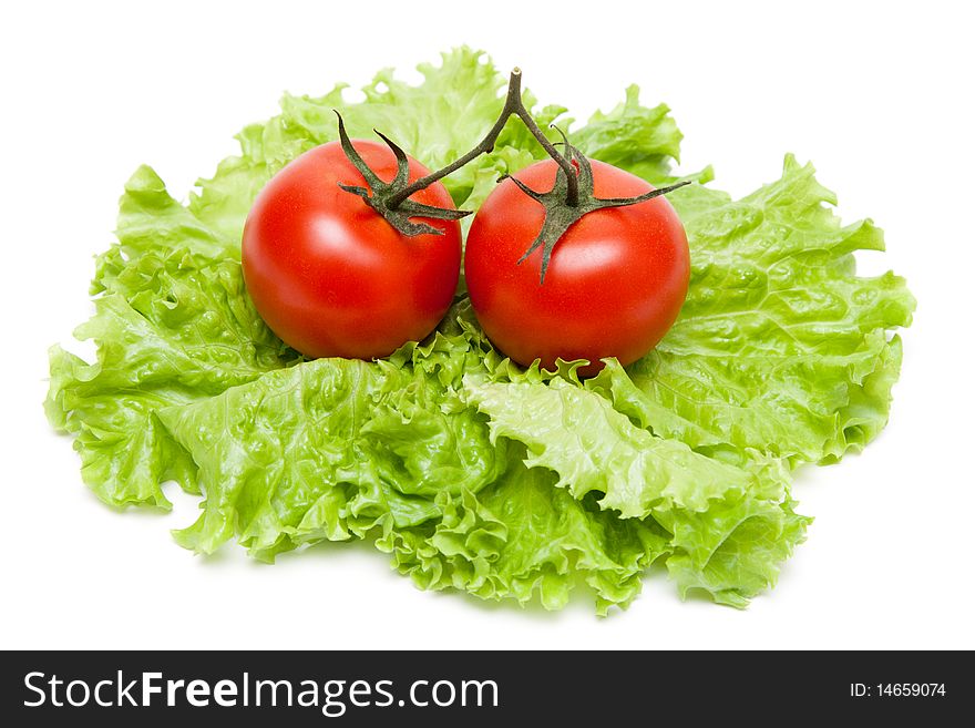 Two ripe tomatoes on become cool sheet of the salad on white background. Two ripe tomatoes on become cool sheet of the salad on white background