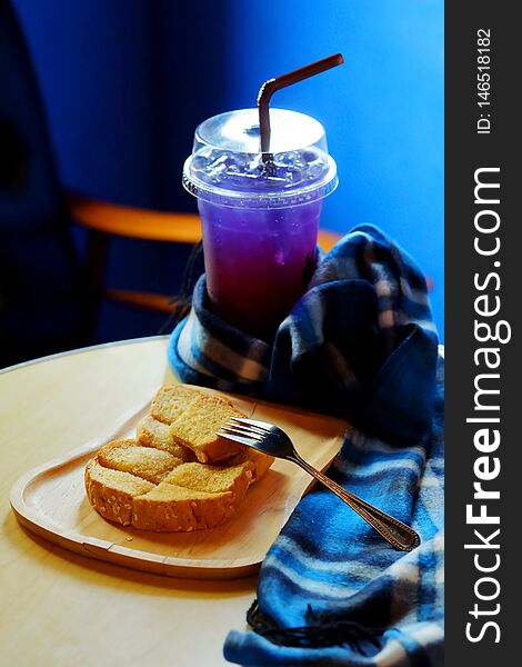 Butter toasted bread on wood trey and ice sour purple butterfly pea juice blue table wood table set with blue tone background