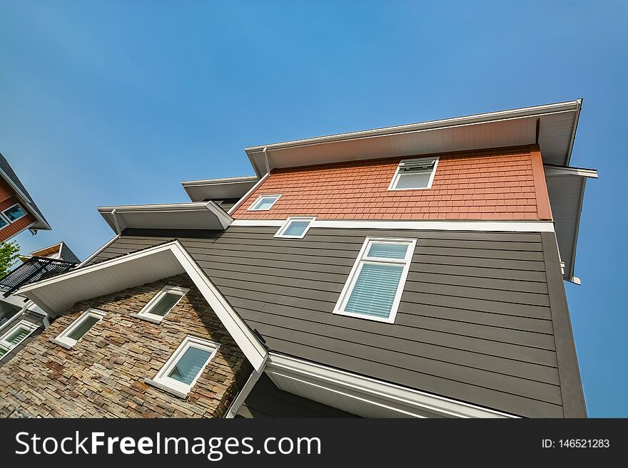 Side wall of brand new residential triplex townhouse on blue sky background. Family house for sale