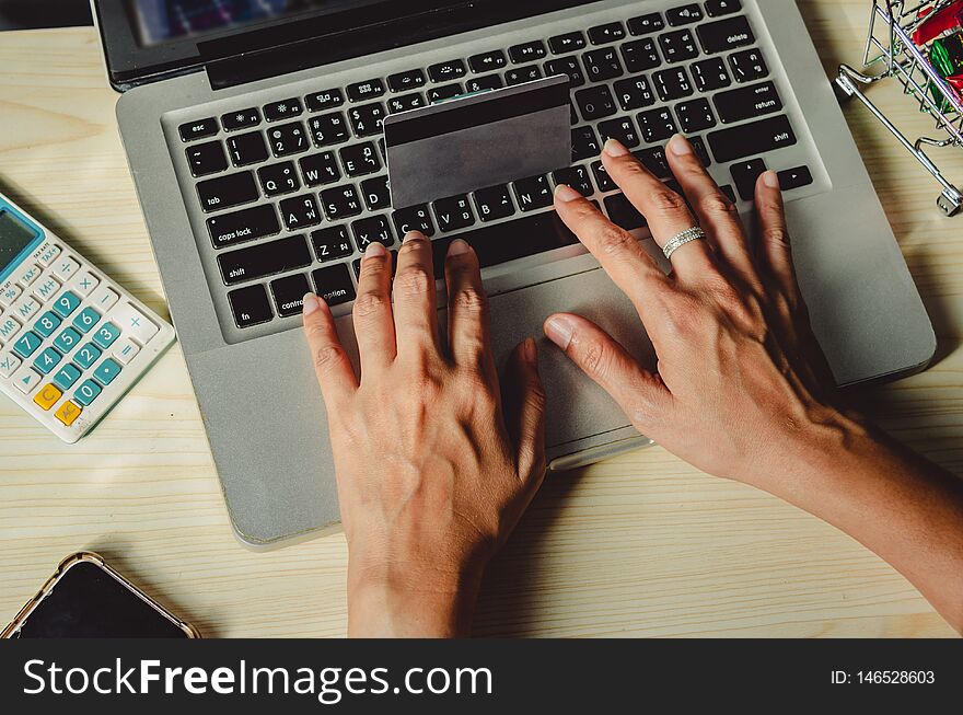 Hands holding a credit card and using a laptop computer on the table. Hands holding a credit card and using a laptop computer on the table