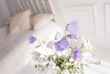 Glass Vase With Lilac And White Floweers  In Light Cozy Bedroom Interior. White Wall, Bed With White Linen, Light Blanket Or Plaid Royalty Free Stock Images