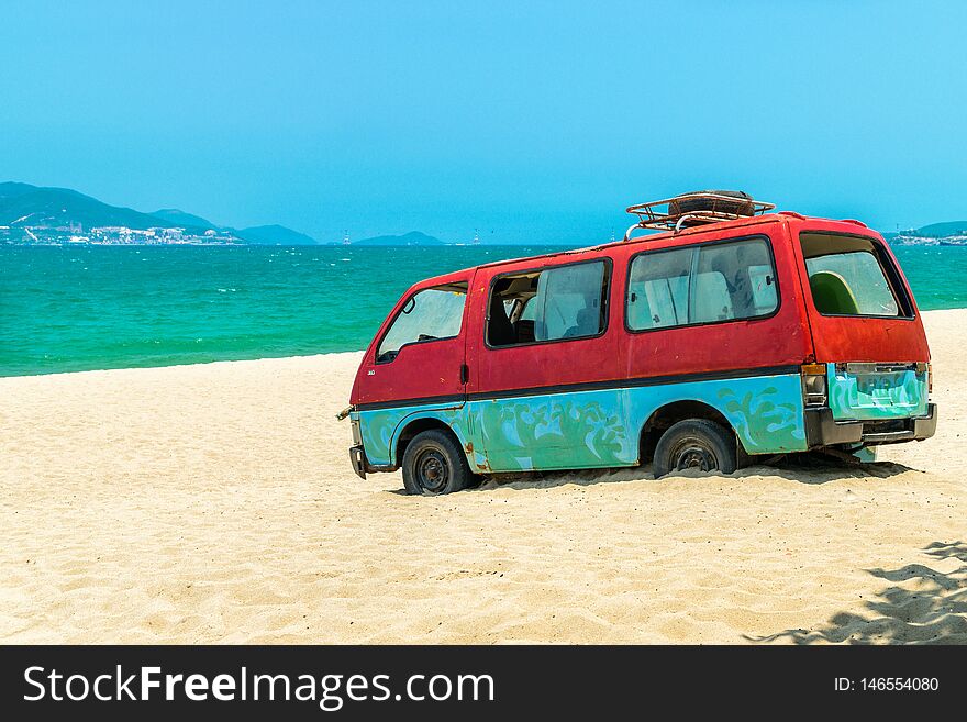 Old Bus In Sand Of Beach With Blue Sea Background